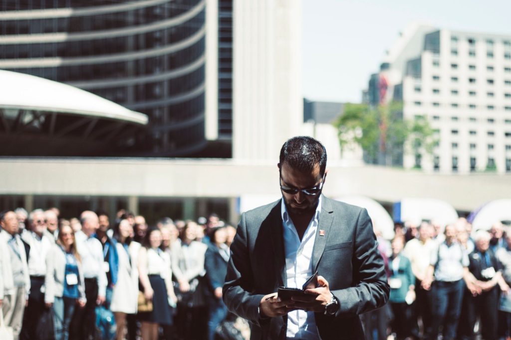 Focused businessman using tablet in a bustling crowd in Toronto's busy urban setting. — The Role of Ogusers in Connecting Buy