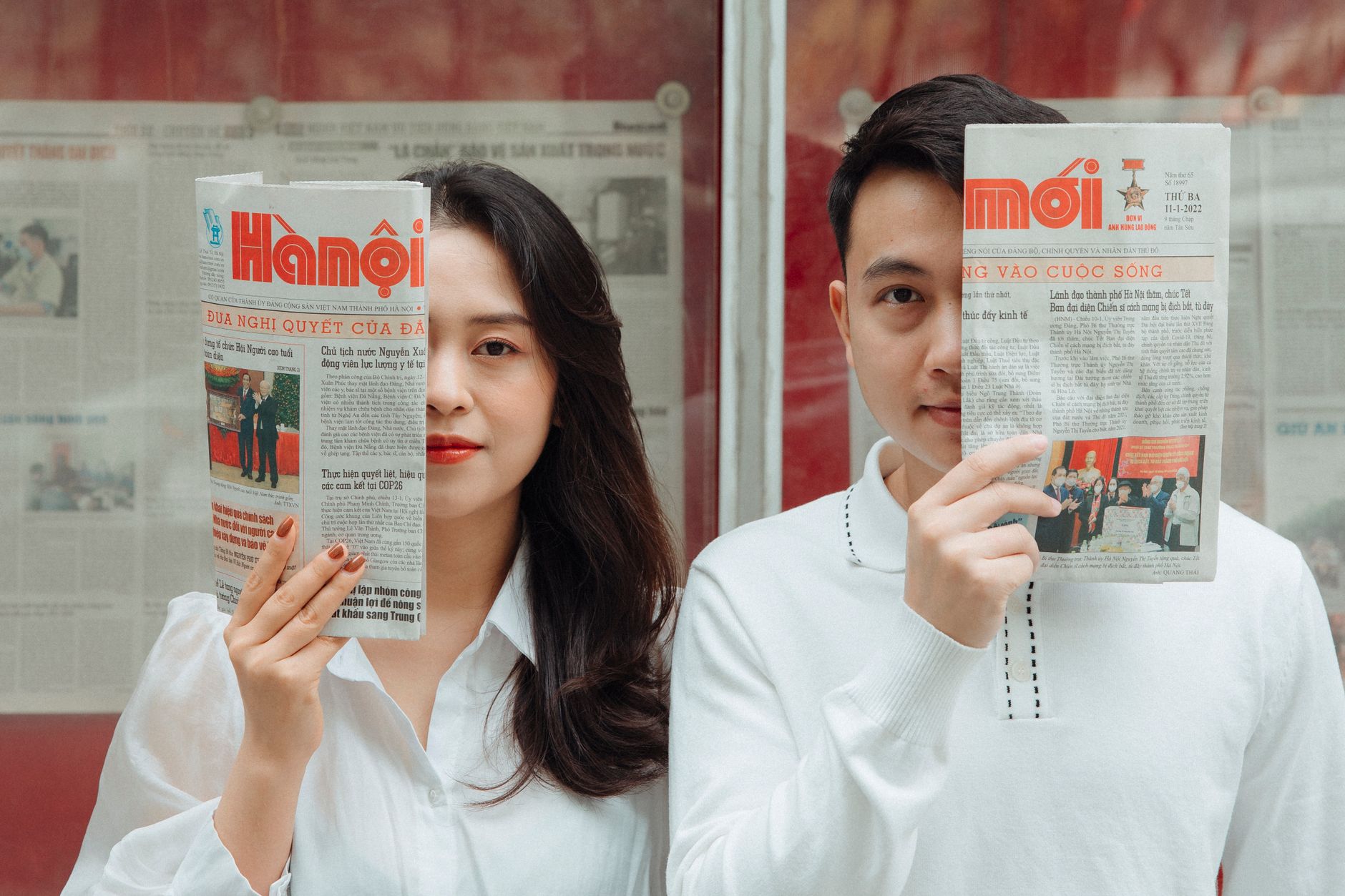 Asian couple playfully posing with Hanoi newspapers indoors, capturing love and connection. — VIP Rewards for Loyal TC Lotter